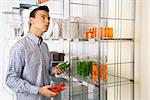 Asian male shopping for dishes and glasses in retail store.