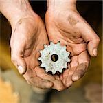 Dirty caucasian male metalmith's hands holding metal leaf.