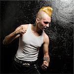 Mid-adult Caucasian male punk with clenched fists looking downward.