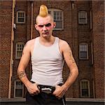 Portrait of a mid-adult Caucasian male punk ouutside with building in background.