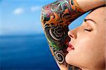 Close up portrait of tattooed woman with Pacific Ocean in background in Maui, Hawaii, USA.