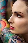 Close-up of attractive Caucasian woman's face and tattooed arm.