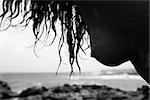 Young Caucasian female nude chest leaning forward with Maui coast in background.