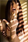 Portrait of pretty Caucasian young woman giving middle finger with mouth open.