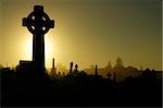 dusk at cemetery, black and yellow tonality, cross in foreground