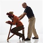 Caucasien massage hommes d'âge mûr thérapeute de massage dos de femme d'âge mûr du Caucase, assis dans une chaise de massage.
