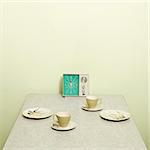 Retro 50's table setting with dishes coffee cups and vintage clock radio.