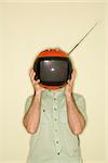 Caucasian mid-adult man holding round red retro television in place of head.
