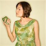 Pretty Caucasian mid-adult woman wearing green vintage dress looking at handheld radio.