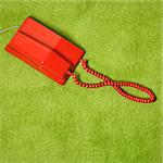Red vintage telephone on 70's green carpet.