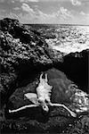 Young nude Asian woman floating in water with arms outstretched in Maui, Hawaii.