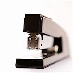 Selective focus of black stapler on white background.