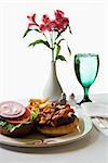 Cheeseburger meal with flowers and glass of water.