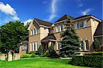 Large upscale residential home with bright green lawn and blue sky