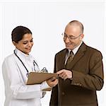 Indian mid adult woman doctor talking with man in business suit.