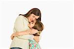 Mother and daughter embracing standing against white background.