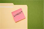 Folder with pink sticky note reading lunch on a green background.