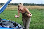 young blond woman with her broken car. The girl is sad