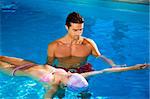 Healthy lifestyle: girl taking swimming lessons in a swimming pool