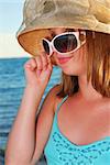 Teenage girl wearing hat and sunglasses on a summer beach