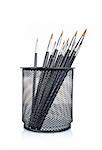 Assortment of various paintbrushes in the basket, reflected on white background