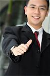 Good looking asian business man standing with arms outstretched ready to shake hands.