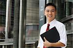 Good looking asian business man smiling with folder in hand.