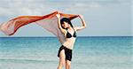 Young girl holding orange cloth in ocean background