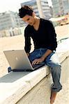 Young cool handsome man uses a personal computer sitting outdoor