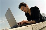 Young man wearing casual shirt uses a notebook outdoor