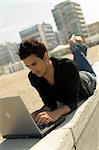 Relaxed young man wearing casual shirt uses a notebook on the beach