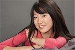 Portrait of a beautiful Asian teenager posing on a gray background with some attitude