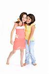 Sisters standing on white background smiling wearing casual clothes