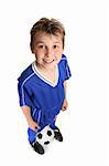 Happy, standing boy wearing soccer uniform with soccer ball against white backdrop. Focus to face.