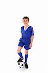 Happy young boy dressed in soccer gear rests his boot on a soccer ball