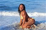 African-American female sitting in waters of chilly ocean