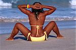 African-American female taking sunbath on beach by ocean