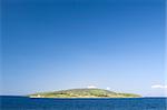 Lonely mediterranean green island against blue sky