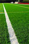 Green sports field with artificial grass and racetrack