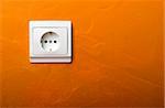 Electric wall plug at a orange wall