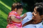 Very cute baby or toddler in bright pink clothings laughing with her mother. Concept: motherly love