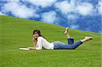 Beautiful woman lying on the grass and reading