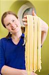 A proud young woman with fresh homemade fettuccine - shallow depth of field with focus on the pasta