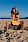 Nude girl with a guitar at the beach
