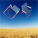 Two lawn chairs in mid-air above a field of wheat with blue sky.