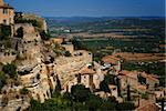 View of ancient medieval hilltop town of Gordes in France, with a view of surrounding landscape.