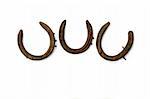 Three old rusty metal horseshoes against a white background.