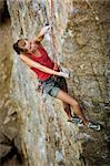 A female rock climber reaches for the next hold.