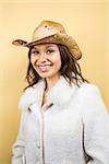 Young adult Caucasian woman wearing cowboy hat smiling at viewer.