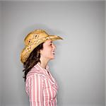 Profile of young Caucasian woman wearing cowboy hat smiling.